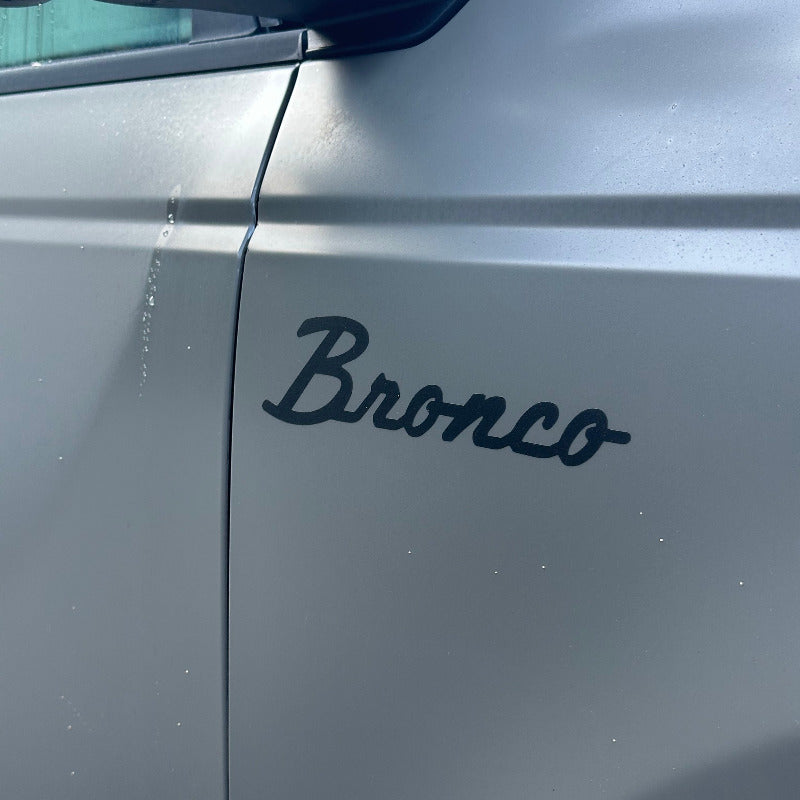 a satin Ford bronco badge decal applied on a fender of a matte march grey bronco 2025