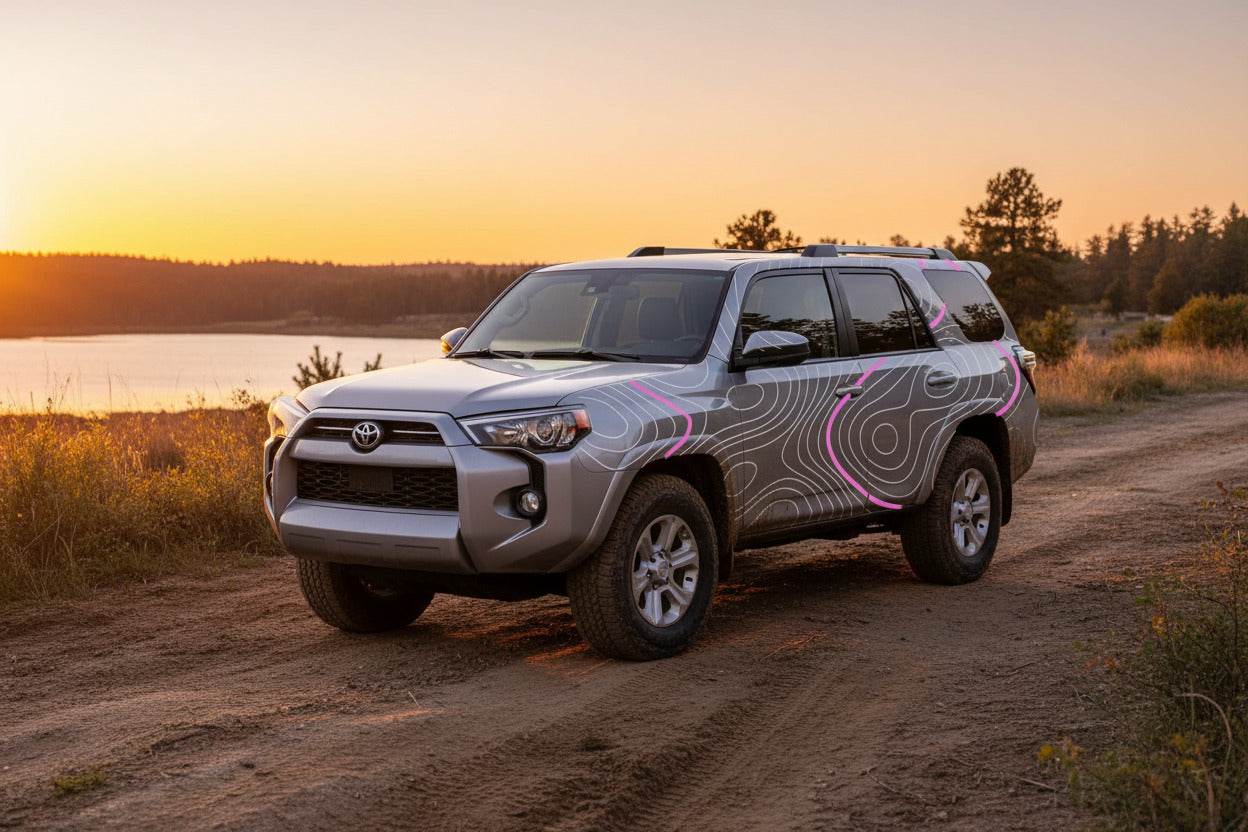 Truck on a dusty road with a custom topographic vinyl decal kit installed pink accent