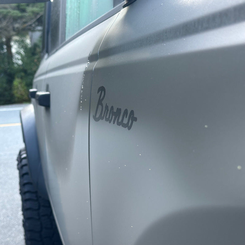 side view of a satin Ford bronco badge decal applied on a fender of a matte march grey bronco 2025

